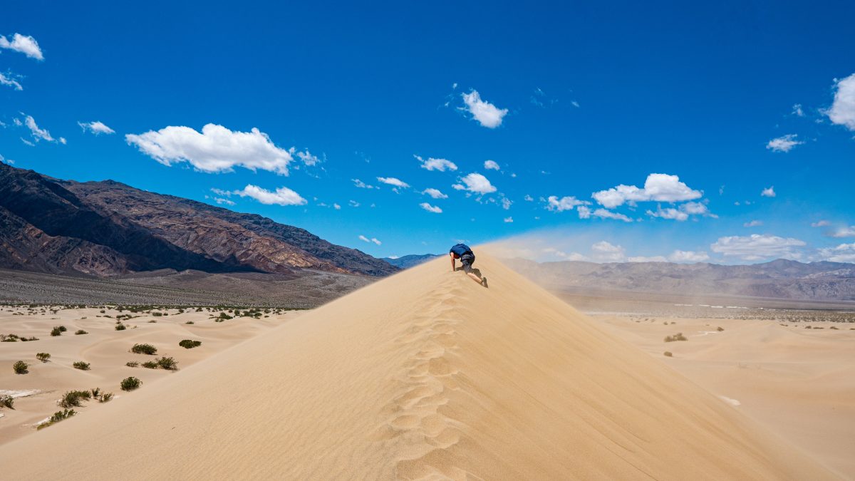 man walking on sand dunes
